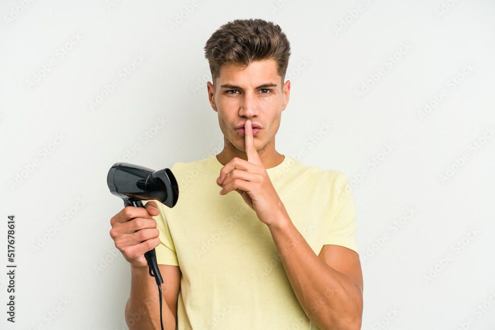 Young caucasian man holding hairdryer isolated on white background keeping a secret or asking for silence. Young caucasian man holding hairdryer isolated on white background keeping a secret or asking for silence.