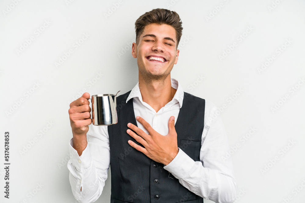 Young caucasian barista man isolated on yellow background laughs out loudly keeping hand on chest. Young caucasian barista man isolated on yellow background laughs out loudly keeping hand on chest.
