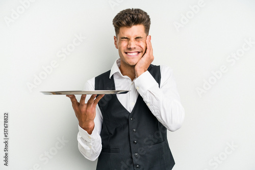 Young caucasian waitress man holding a tray isolated on white background covering ears with hands.