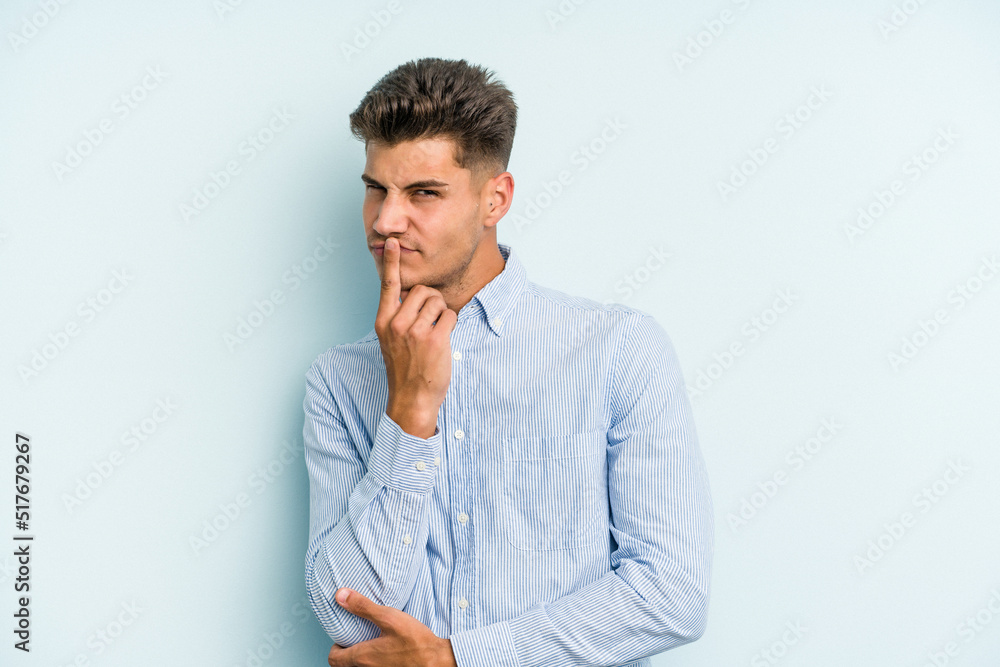 Young caucasian man isolated on blue background contemplating, planning a strategy, thinking about the way of a business. Young caucasian man isolated on blue background contemplating, planning a strategy, thinking about the way of a business.