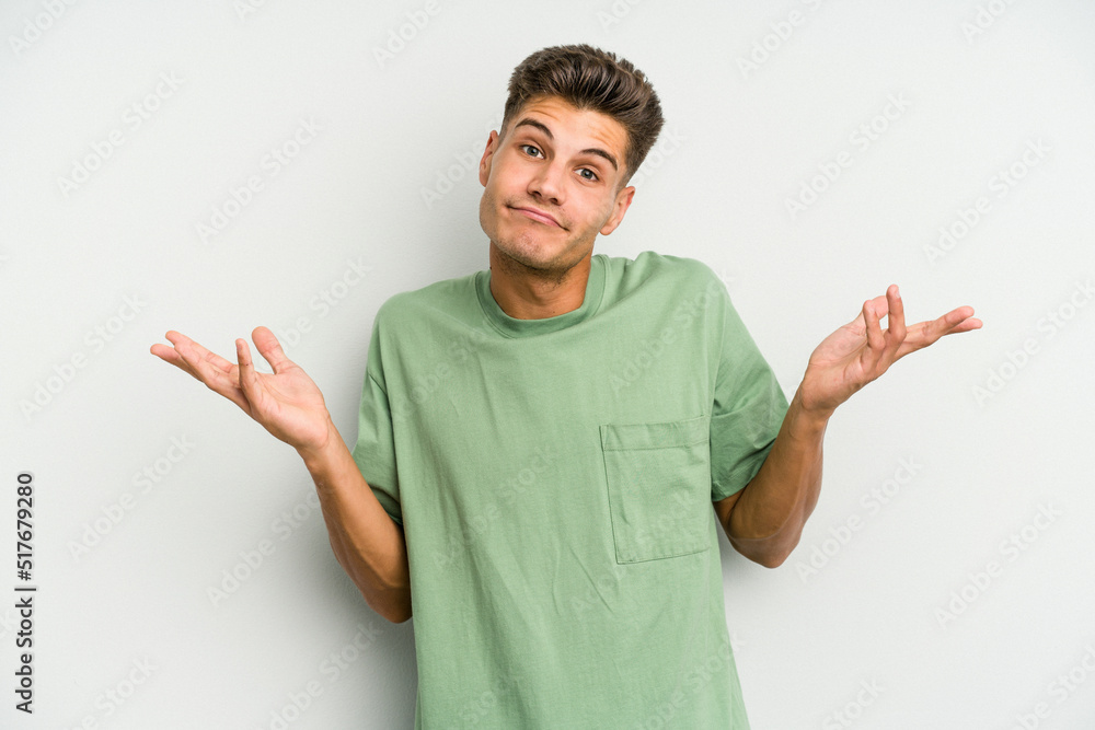 Young caucasian man isolated on white background doubting and shrugging shoulders in questioning gesture. Young caucasian man isolated on white background doubting and shrugging shoulders in questioning gesture.