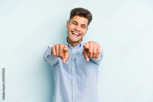 Young caucasian man isolated on blue background pointing to front with fingers.