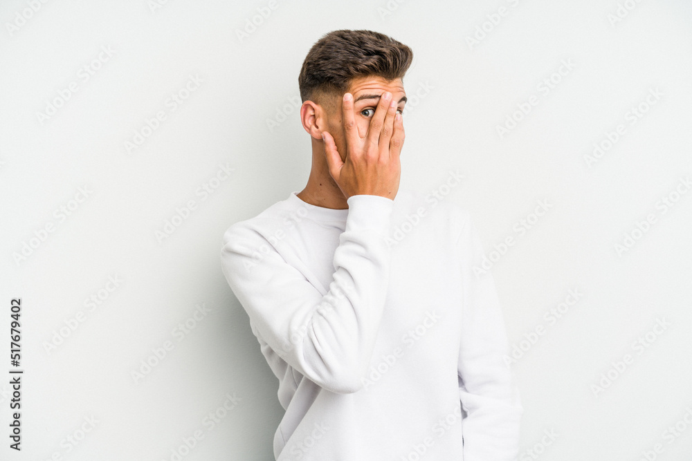 Young caucasian man isolated on white background blink through fingers frightened and nervous. Young caucasian man isolated on white background blink through fingers frightened and nervous.