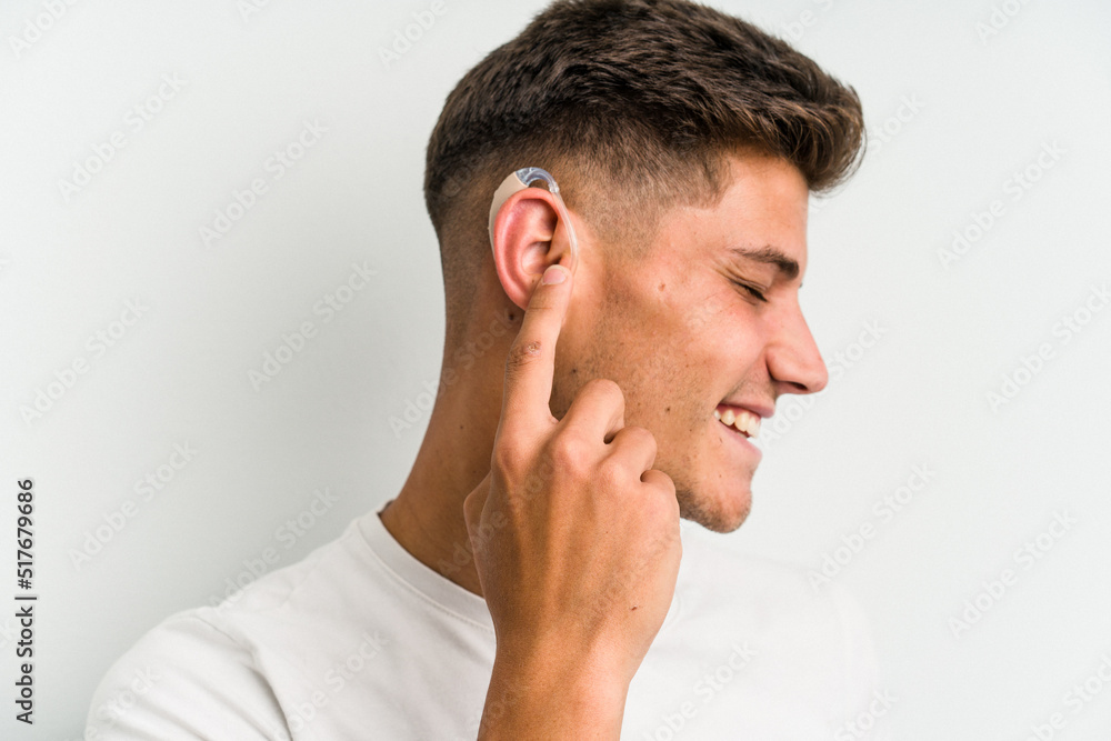 Fototapeta premium Young caucasian man wearing a hearing aid isolated on white background