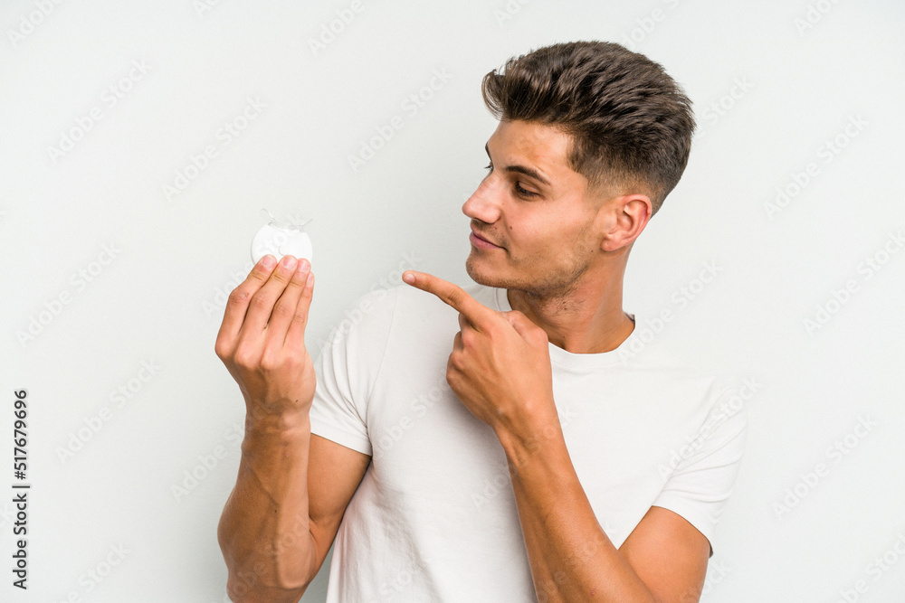 Young caucasian man holding teeth whitener isolated on white background Young caucasian man holding teeth whitener isolated on white background