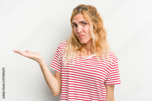 Young caucasian woman isolated on white background doubting and shrugging shoulders in questioning gesture.