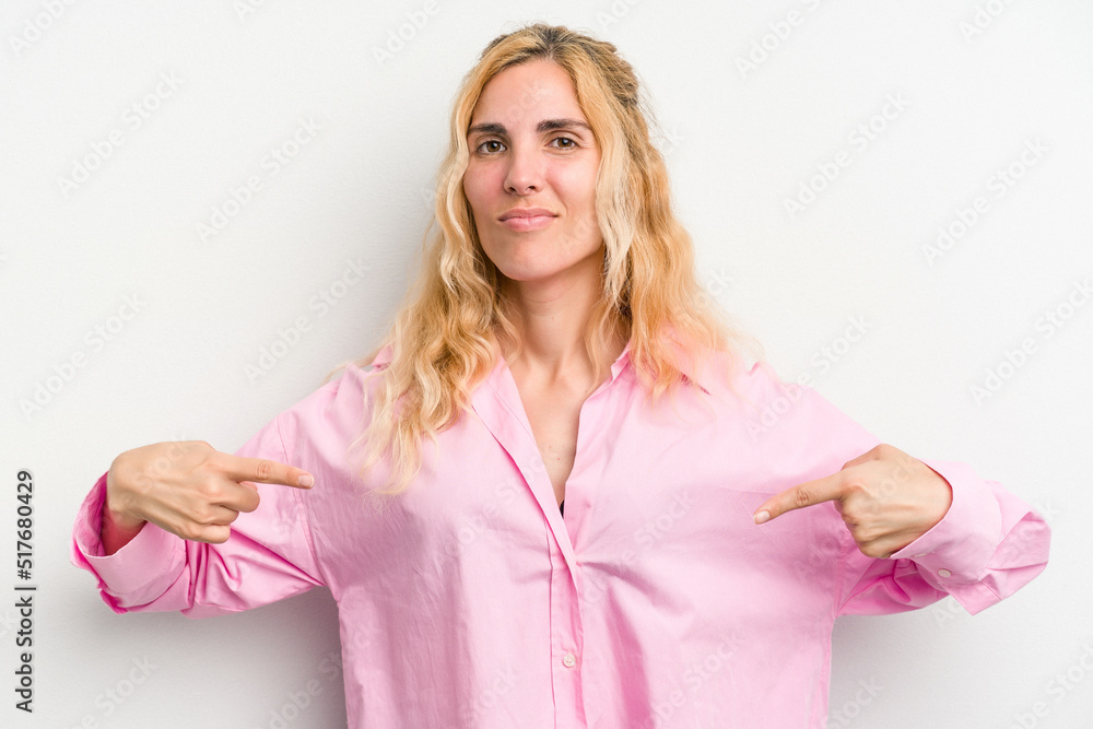 Young caucasian woman isolated on white background person pointing by hand to a shirt copy space, proud and confident