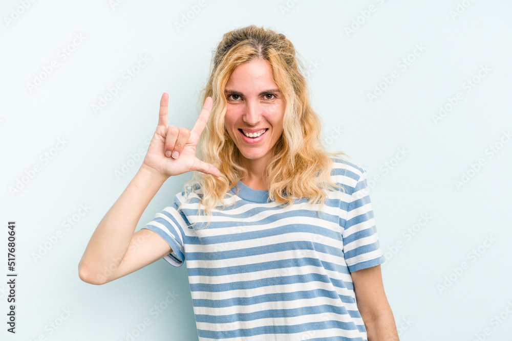 Young caucasian woman isolated on blue background showing a horns gesture as a revolution concept. Young caucasian woman isolated on blue background showing a horns gesture as a revolution concept.