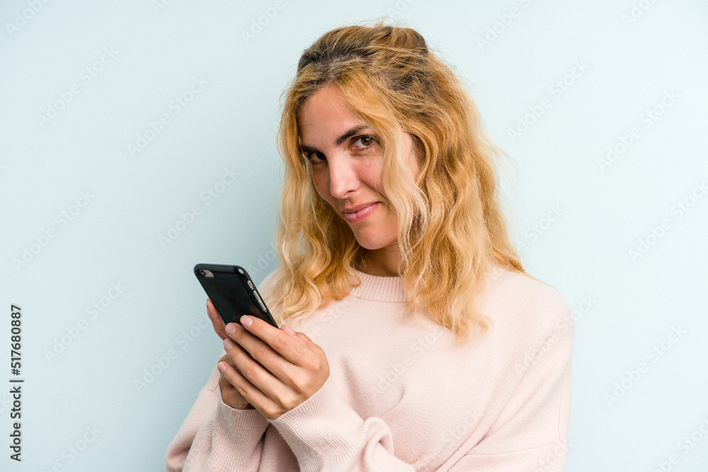 Young caucasian woman holding mobile phone isolated on blue background Young caucasian woman holding mobile phone isolated on blue background
