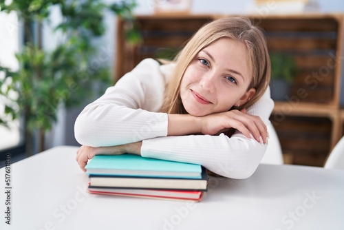 Young caucasian woman smiling confident leaning on books at home