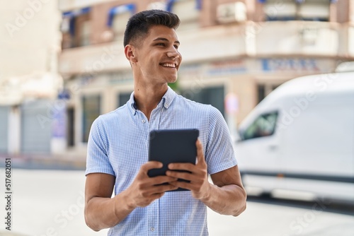 Young hispanic man smiling confident using touchpad at street © Krakenimages.com