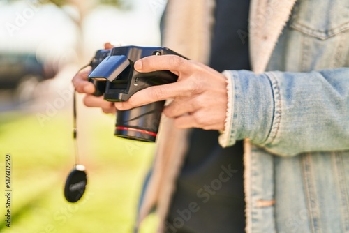 Young hispanic man using professional camera at park