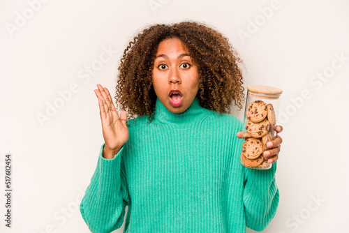 Young African American woman holding a cookies jar isolated on white background surprised and shocked. photo