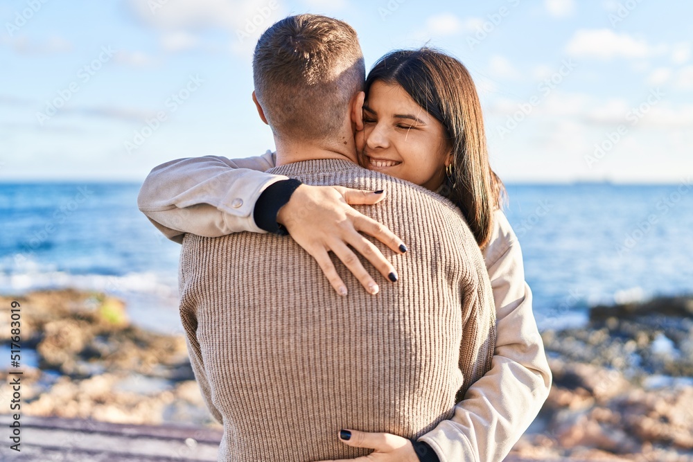 Obraz premium Man and woman couple smiling confident hugging each other standing at seaside