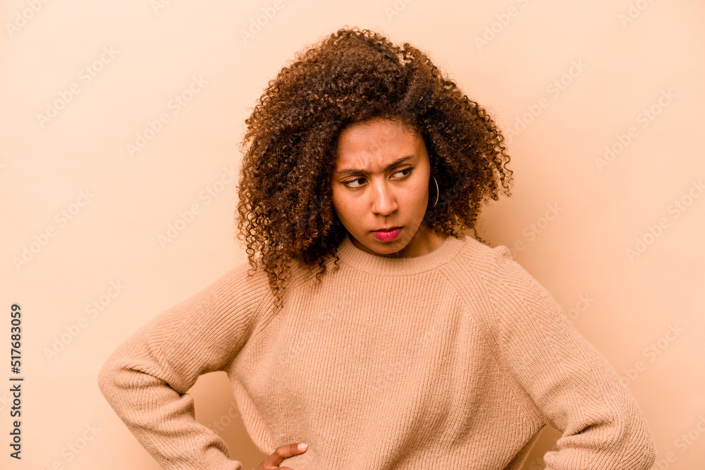 Young African American woman isolated on beige background confused, feels doubtful and unsure. Young African American woman isolated on beige background confused, feels doubtful and unsure.