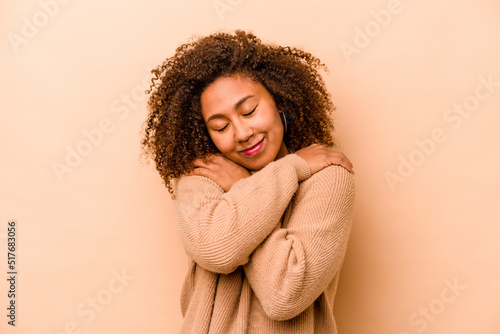 Photo Young African American woman isolated on beige background hugs, smiling carefree and happy