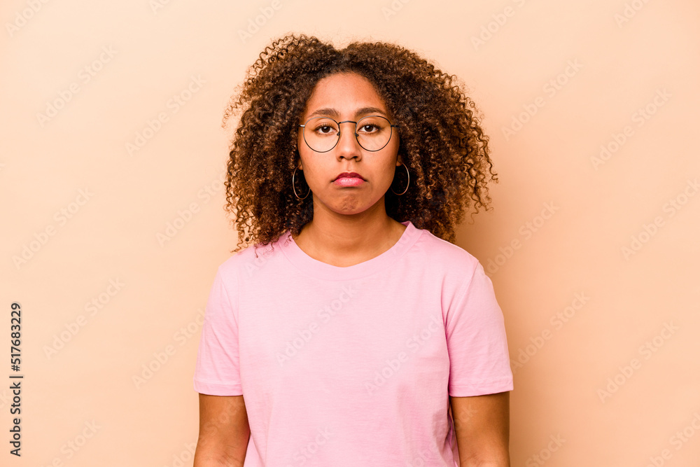 Young African American woman isolated on beige background sad, serious face, feeling miserable and displeased. Young African American woman isolated on beige background sad, serious face, feeling miserable and displeased.