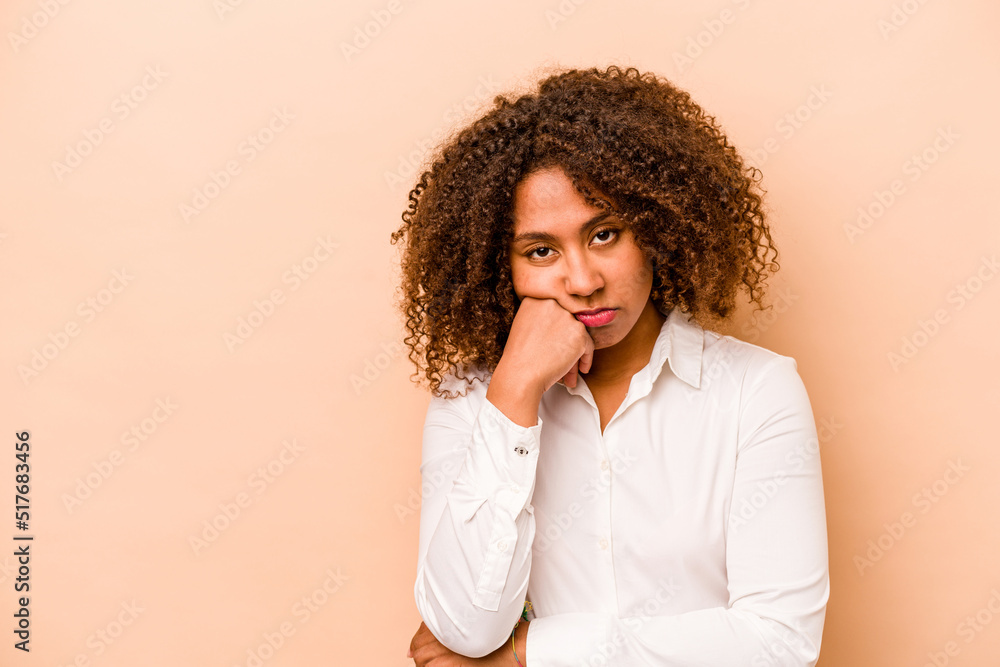 Young African American woman isolated on beige background who feels sad and pensive, looking at copy space. Young African American woman isolated on beige background who feels sad and pensive, looking at copy space.