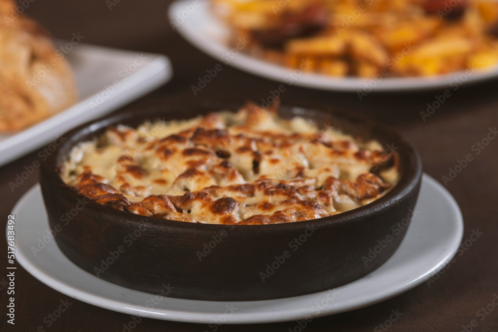 Mushroom and meat casserole covered with melted cheese and served in a dark dish on the table Mushroom and meat casserole covered with melted cheese and served in a dark dish on the table