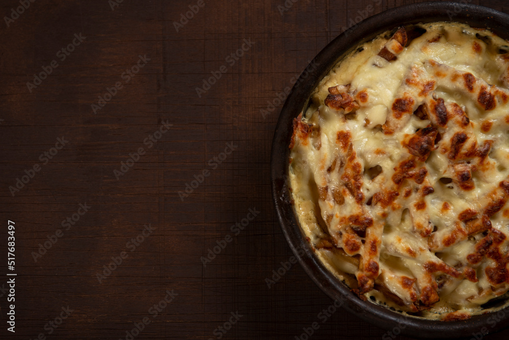 Mushroom and meat casserole covered with melted cheese and served in a dark dish on the table Mushroom and meat casserole covered with melted cheese and served in a dark dish on the table
