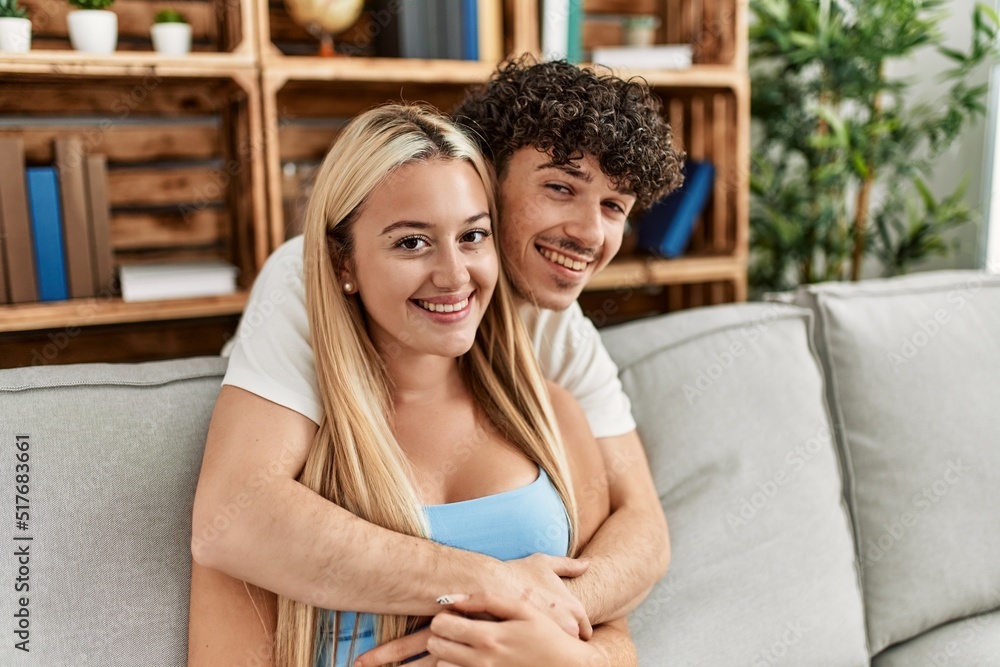 Young couple sitting on the sofa hugging at home. Young couple sitting on the sofa hugging at home.