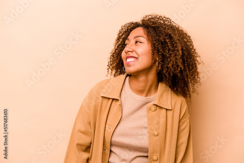 Young African American woman isolated on beige background relaxed and happy laughing, neck stretched showing teeth. © Asier