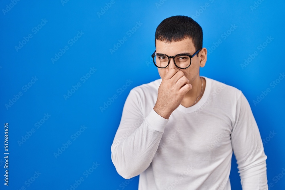 Young arab man wearing casual white shirt and glasses smelling ...