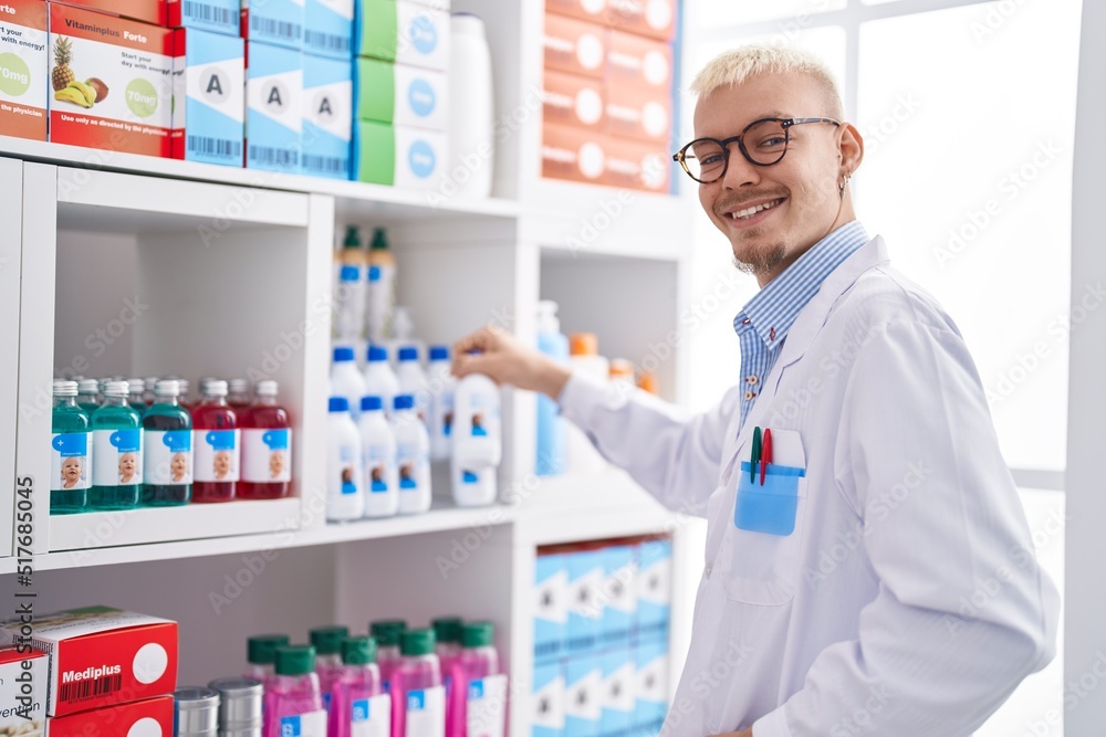 Young caucasian man pharmacist holding medicine bottle at pharmacy