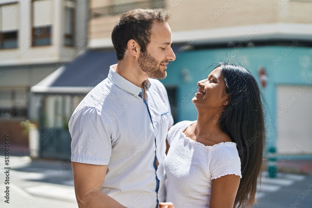 Man and woman interracial couple hugging each other at street Man and woman interracial couple hugging each other at street
