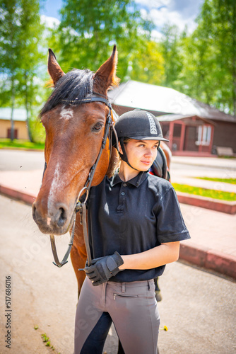 Lovely young woman wearing helmet stroking to her brown horse © dtatiana
