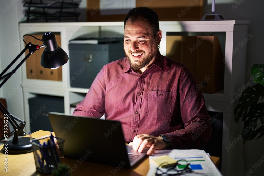 Plus size hispanic man with beard working at the office at night with a happy and cool smile on face. lucky person. Plus size hispanic man with beard working at the office at night with a happy and cool smile on face. lucky person.
