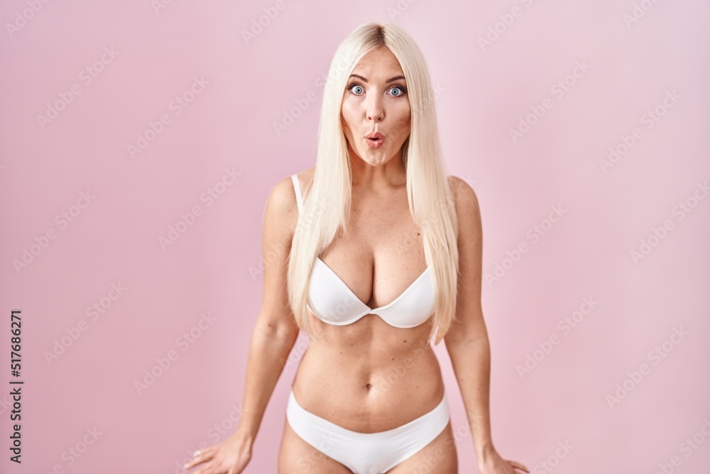 Fototapeta premium Caucasian woman wearing lingerie over pink background afraid and shocked with surprise expression, fear and excited face.
