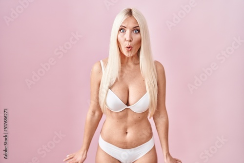 Caucasian woman wearing lingerie over pink background afraid and shocked with surprise expression, fear and excited face.
