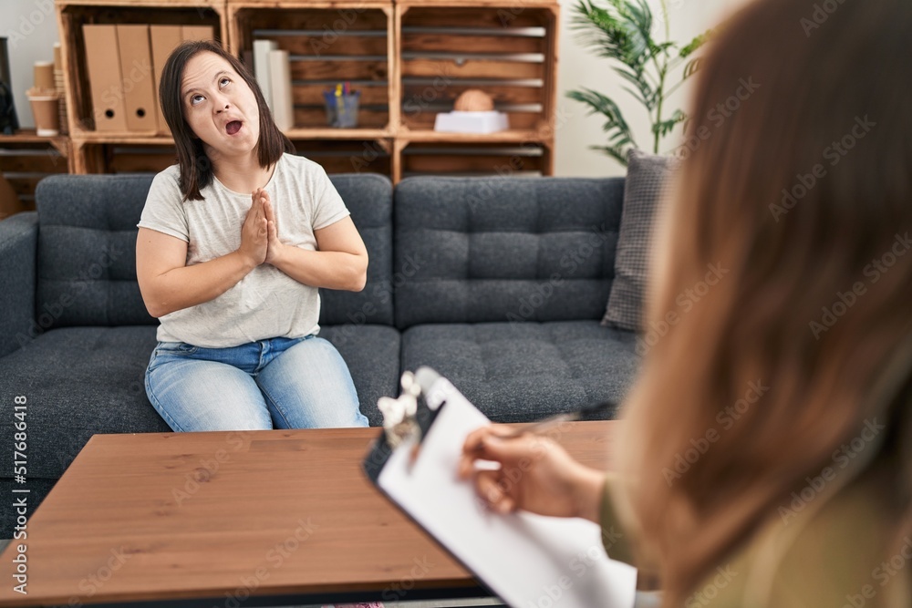 Hispanic girl with down syndrome doing therapy begging and praying with hands together with hope expression on face very emotional and worried. begging. Hispanic girl with down syndrome doing therapy begging and praying with hands together with hope expression on face very emotional and worried. begging.
