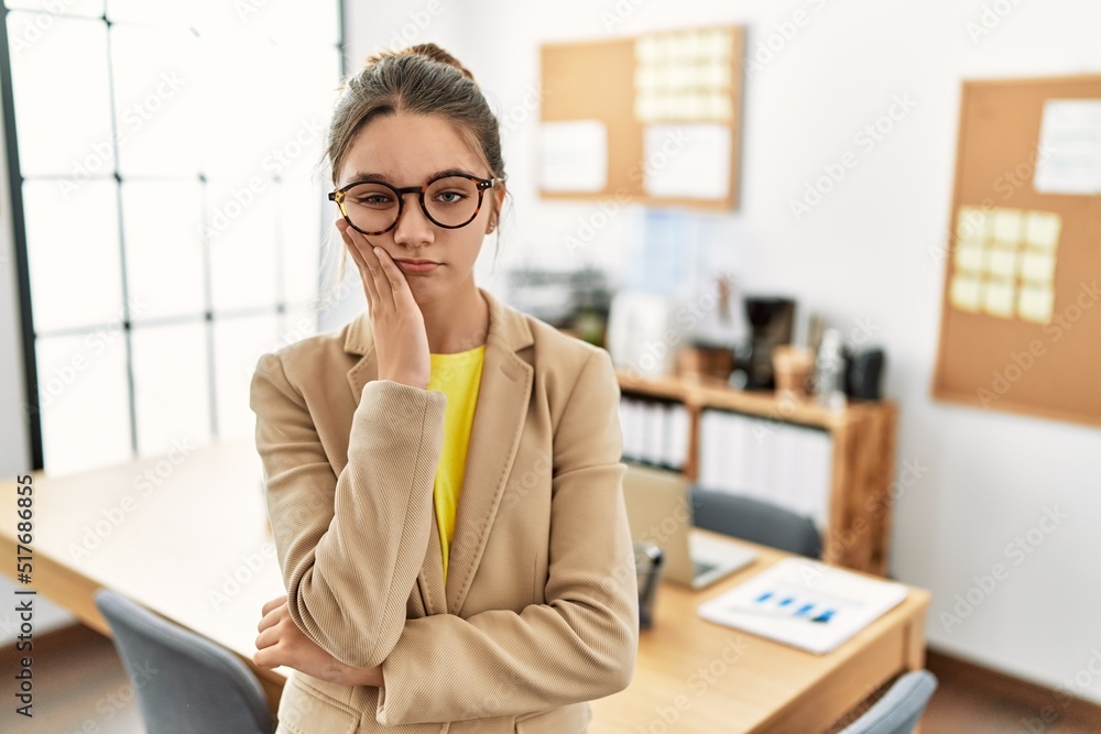 Young brunette teenager wearing business style at office thinking looking tired and bored with depression problems with crossed arms. Young brunette teenager wearing business style at office thinking looking tired and bored with depression problems with crossed arms.