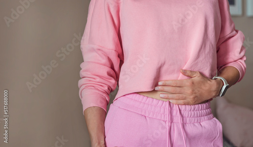 Unrecognized woman standing and holding her hands on her belly . Woman suffering from abdominal pain