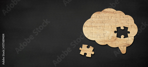 Brain shaped wooden jigsaw puzzle on black background, a missing piece of the brain puzzle, mental health and problems with memory