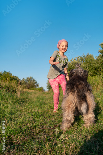 Little girl hugging playing with dog outdoor. Family walking having fun spending time together on nature. Child with pet friend in summer meadow. Active lifestyle leisure candid real authentic people.
