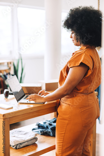 Black businesswoman using a laptop in her clothing store