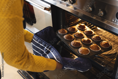 Fotografie Image of midsection of african american senior woman taking out cupcakes from ov