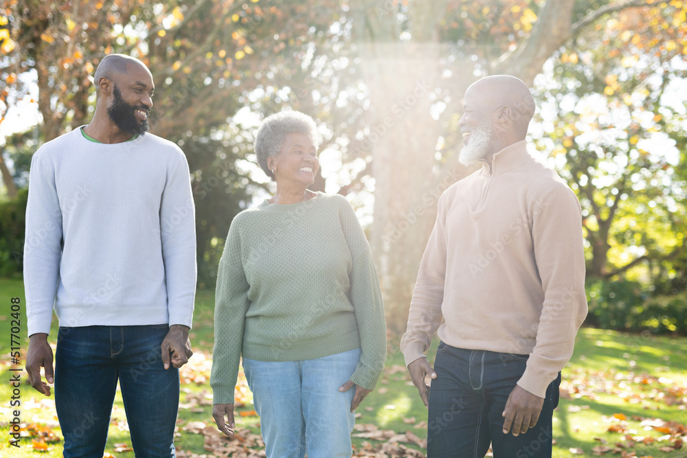 Image of happy african american parents and adult son posing in garden Image of happy african american parents and adult son posing in garden