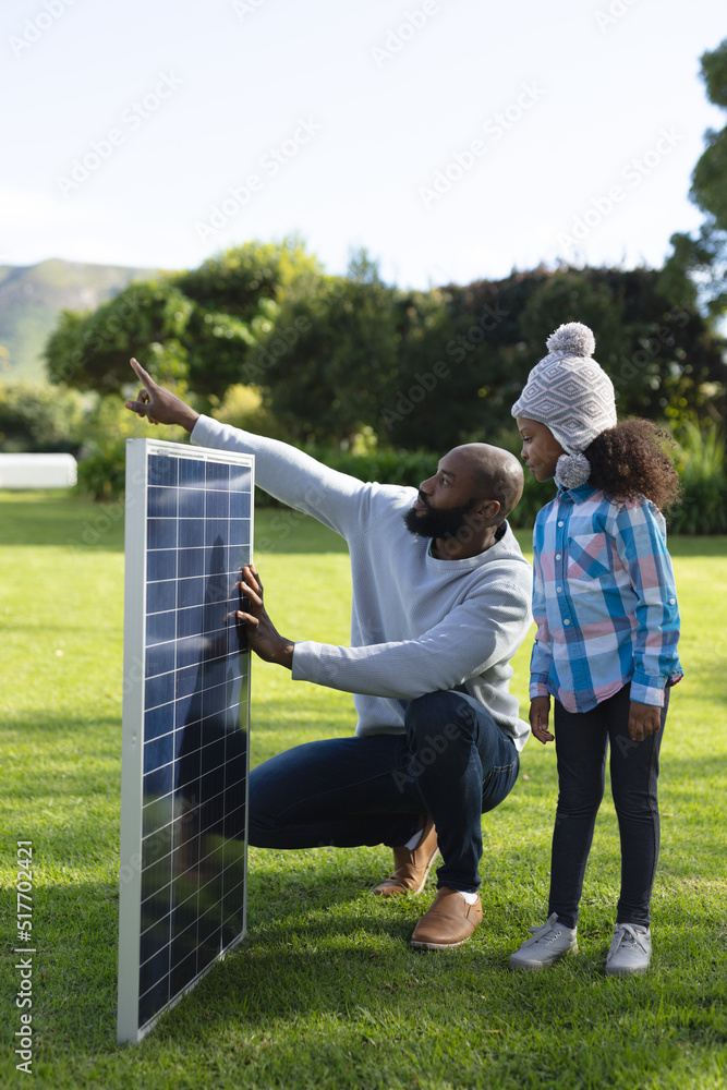 Vertical image of happy african american father showing solar panels to daughter Vertical image of happy african american father showing solar panels to daughter