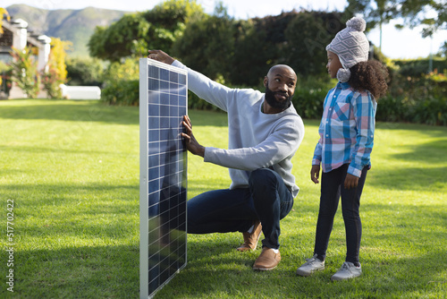 Image of happy african american father showing solar panels to daughter
