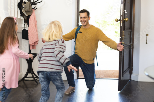 Image of caucasian father returning home from work and welcoming with children