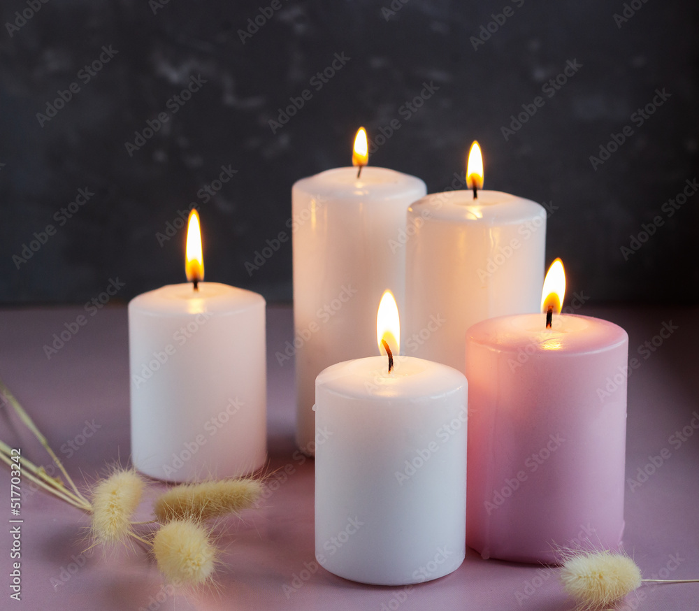 Set of white and pink wax candles with dried flowers in low lights Set of white and pink wax candles with dried flowers in low lights