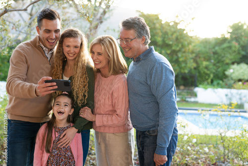 Image of happy multi generation caucasian family taking selfie after dinner on patio