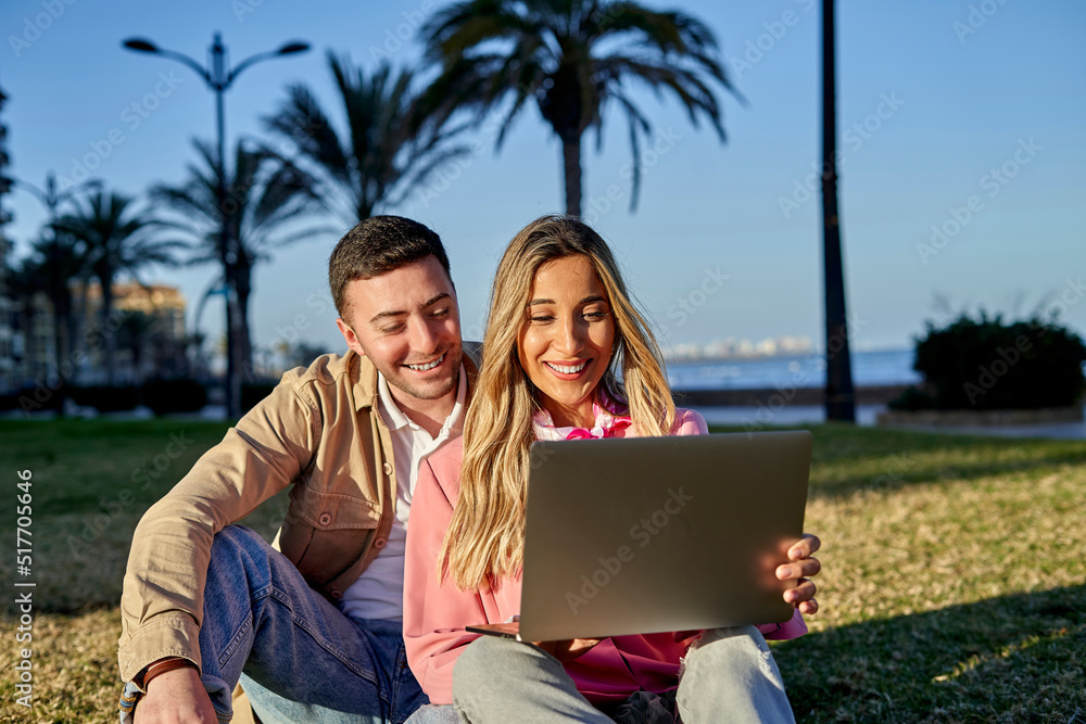 Young couple using laptop on lawn in a park Young couple using laptop on lawn in a park