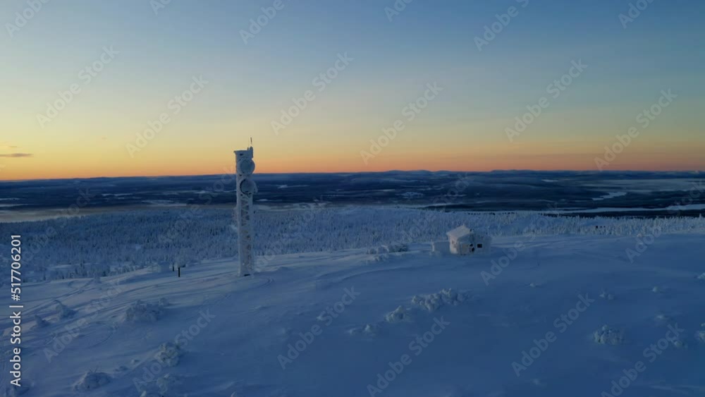 Aerial view orbiting snow covered Lapland remote cabin and communications tower overlooking polar wilderness at sunrise Aerial view orbiting snow covered Lapland remote cabin and communications tower overlooking polar wilderness at sunrise