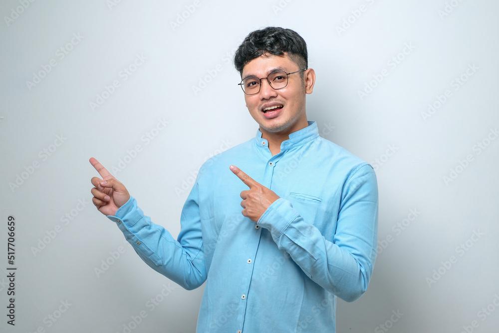 Young asian chinese man Surprised pointing with hand finger to the side, open mouth amazed expression. Young asian chinese man Surprised pointing with hand finger to the side, open mouth amazed expression.