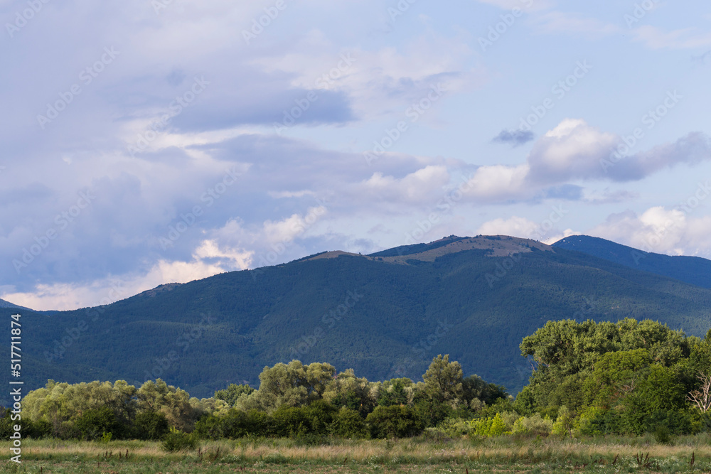 Fototapeta premium Thunderhead covers the Balkans. Downpour is approaching agricultural land. Villages, fields and forests of Bulgaria before the rain. The terrain in southern Europe. Panorama.